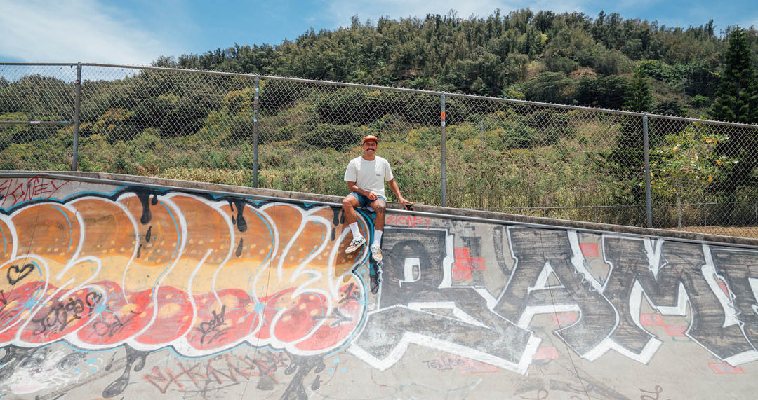 Jack Soren sitting at edge of skatepark with board by his side