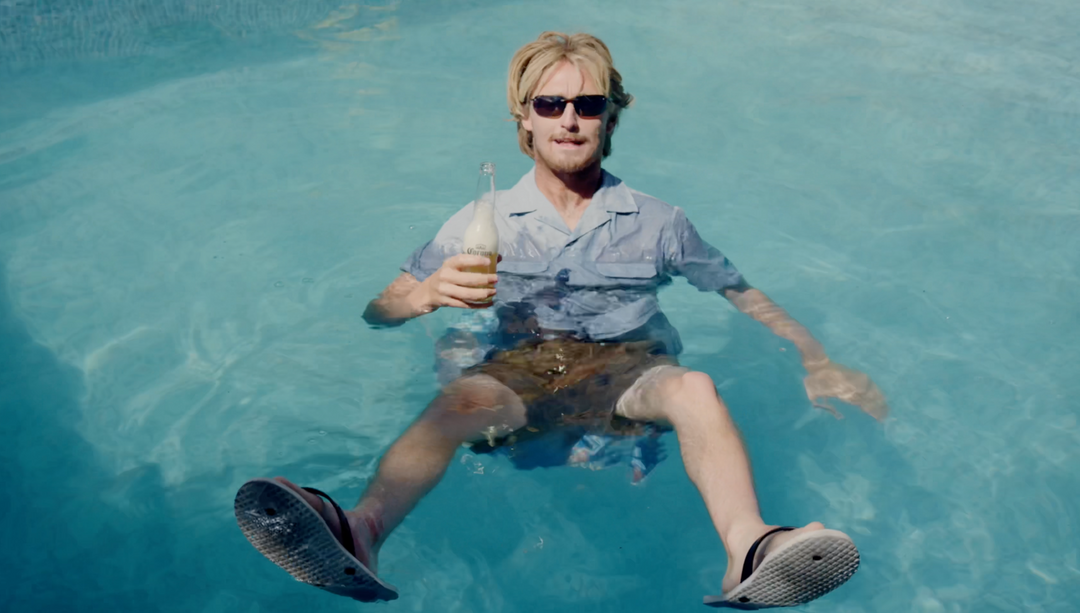 Josiah Amico sitting fully clothed in water holding a beer