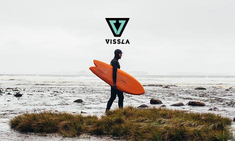 Man in hooded wetsuit with an orange fish surfboard